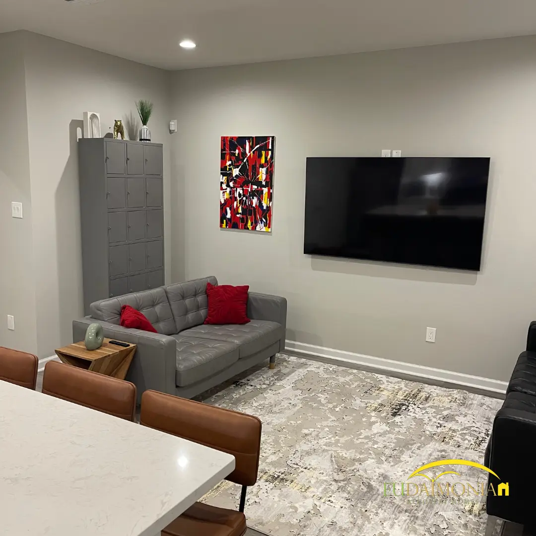 Living room with a gray sofa, armchair and a wall-mounted television.