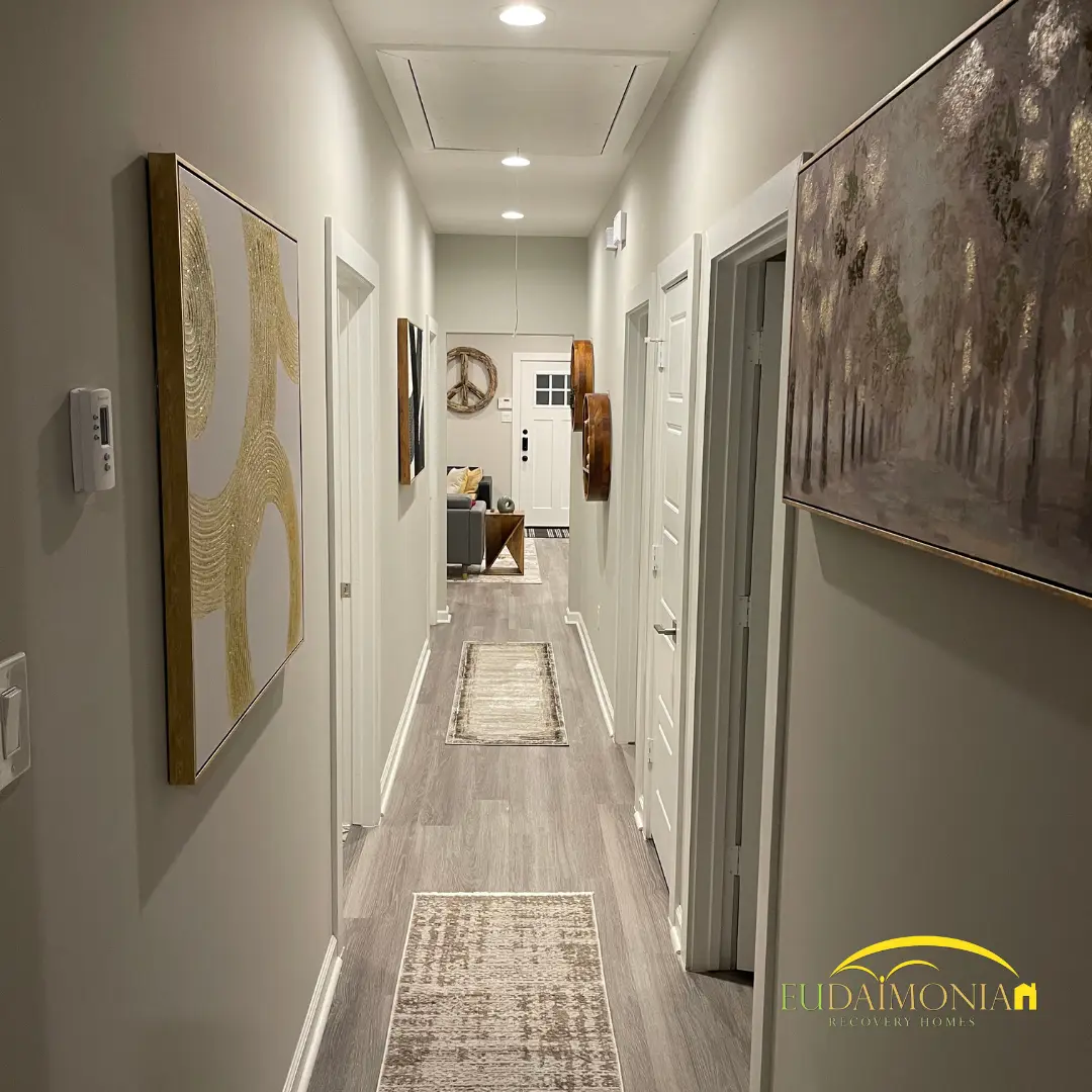 Hallway with framed artwork and a runner on gray flooring.