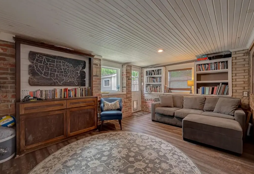 Sitting room with built-in bookshelves, a sofa and a round rug.