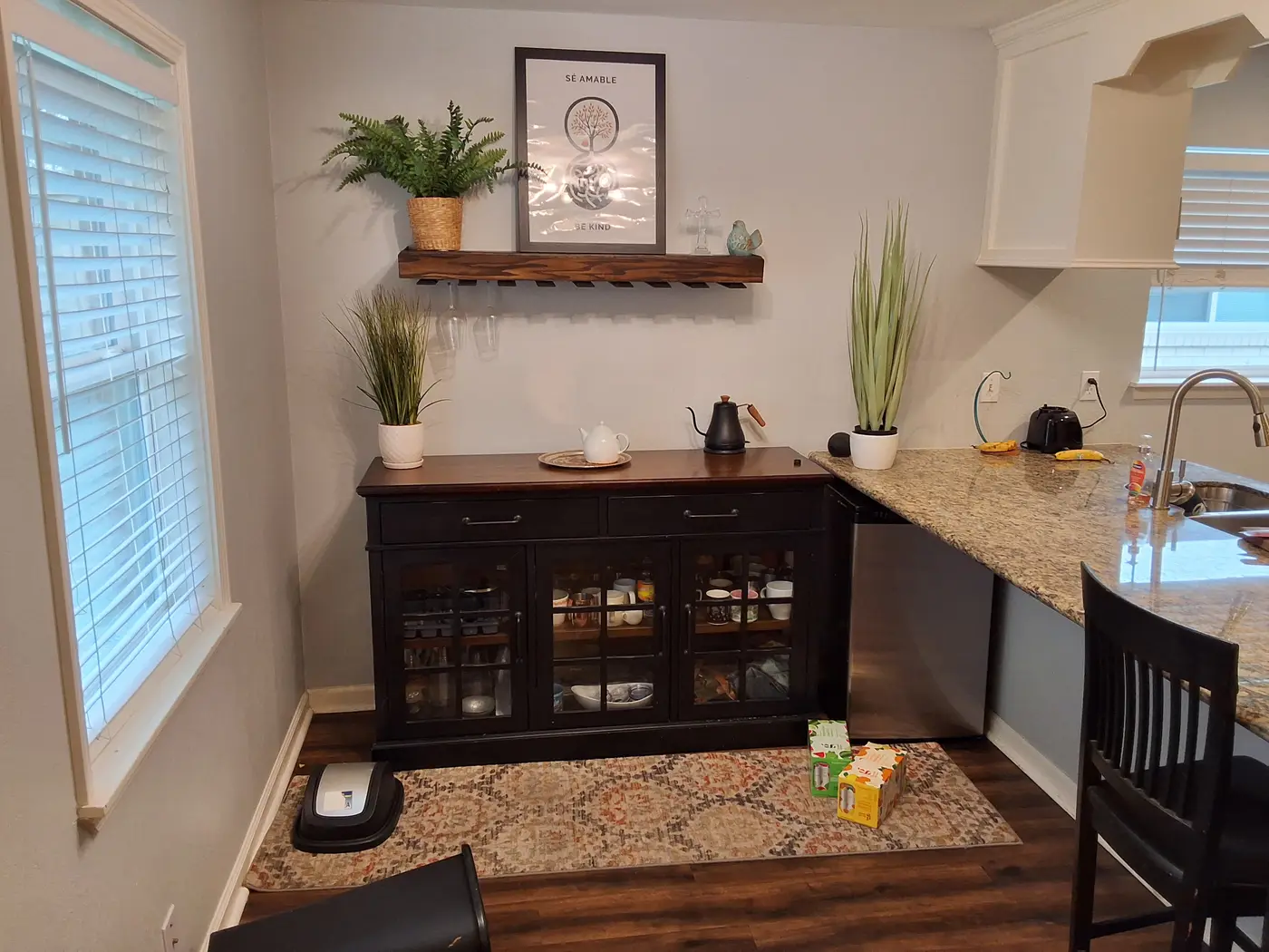 Kitchen with granite counters, shelving and potted herbs.