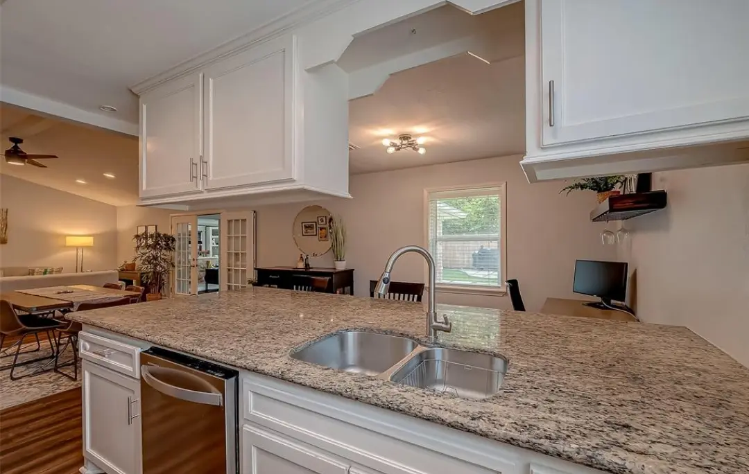 Kitchen with a granite island, double sink and stainless dishwasher.