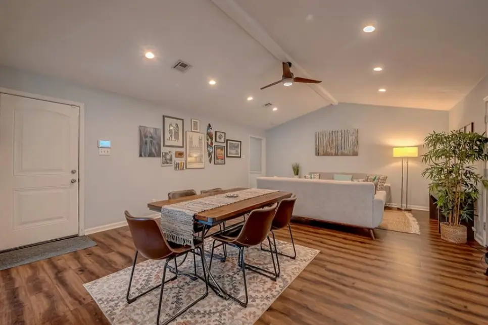 Open-plan dining and living area with a wooden table and leather chairs.