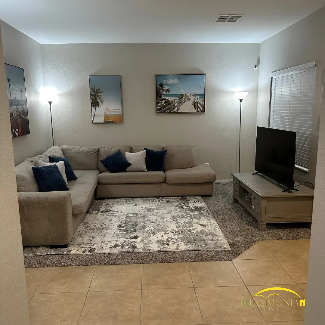 Living room with a sectional, television and framed prints.