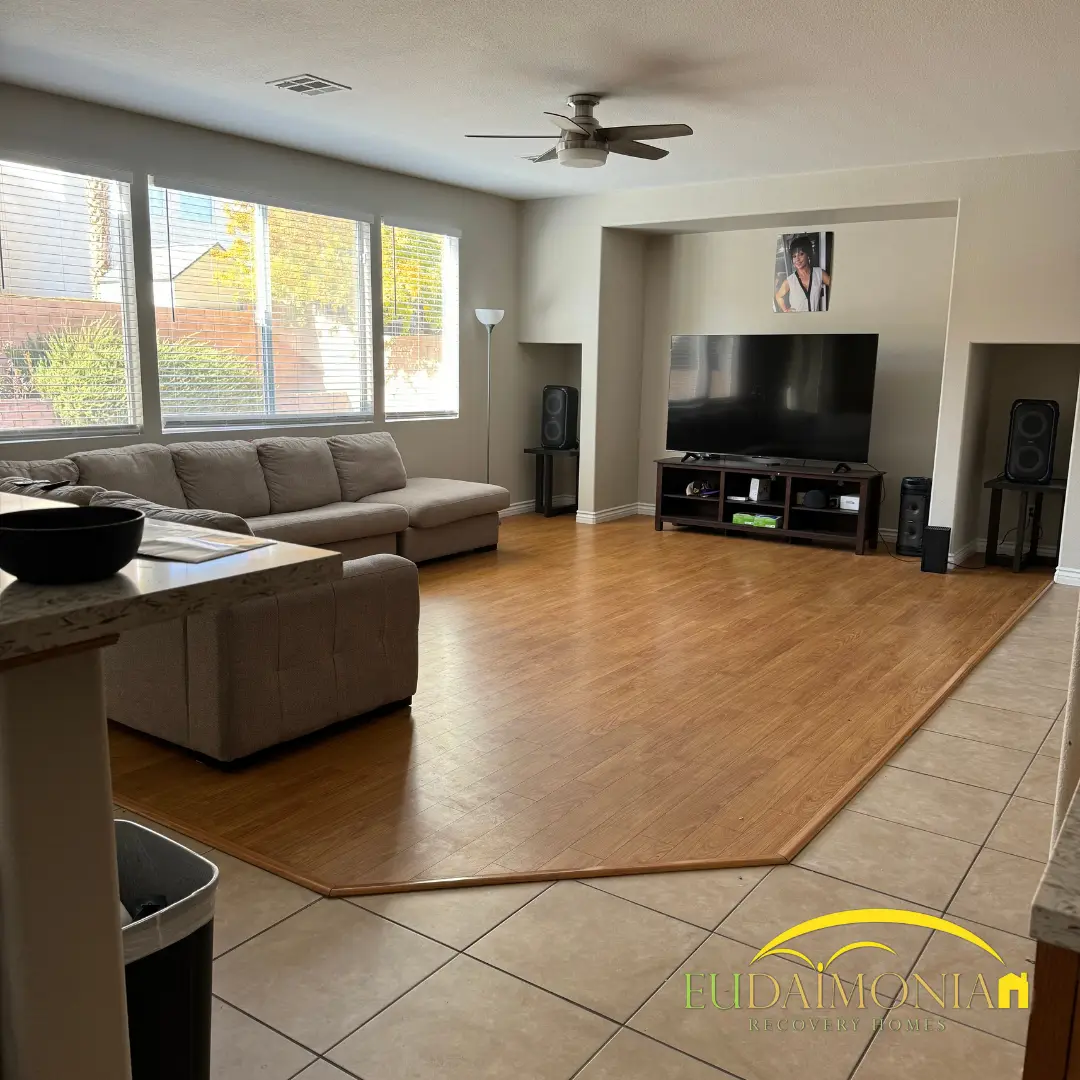 Living room with a sectional and television on tiled flooring.
