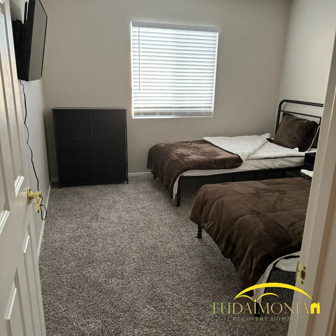 Bedroom with two single beds in brown bedding beneath a window.