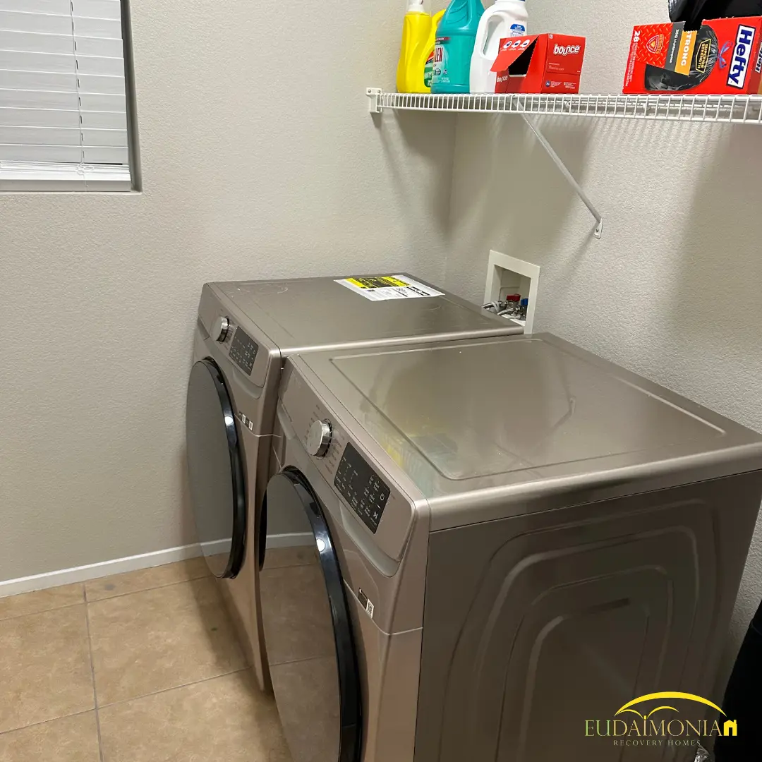 Laundry with a washer and dryer beneath a wire shelf.