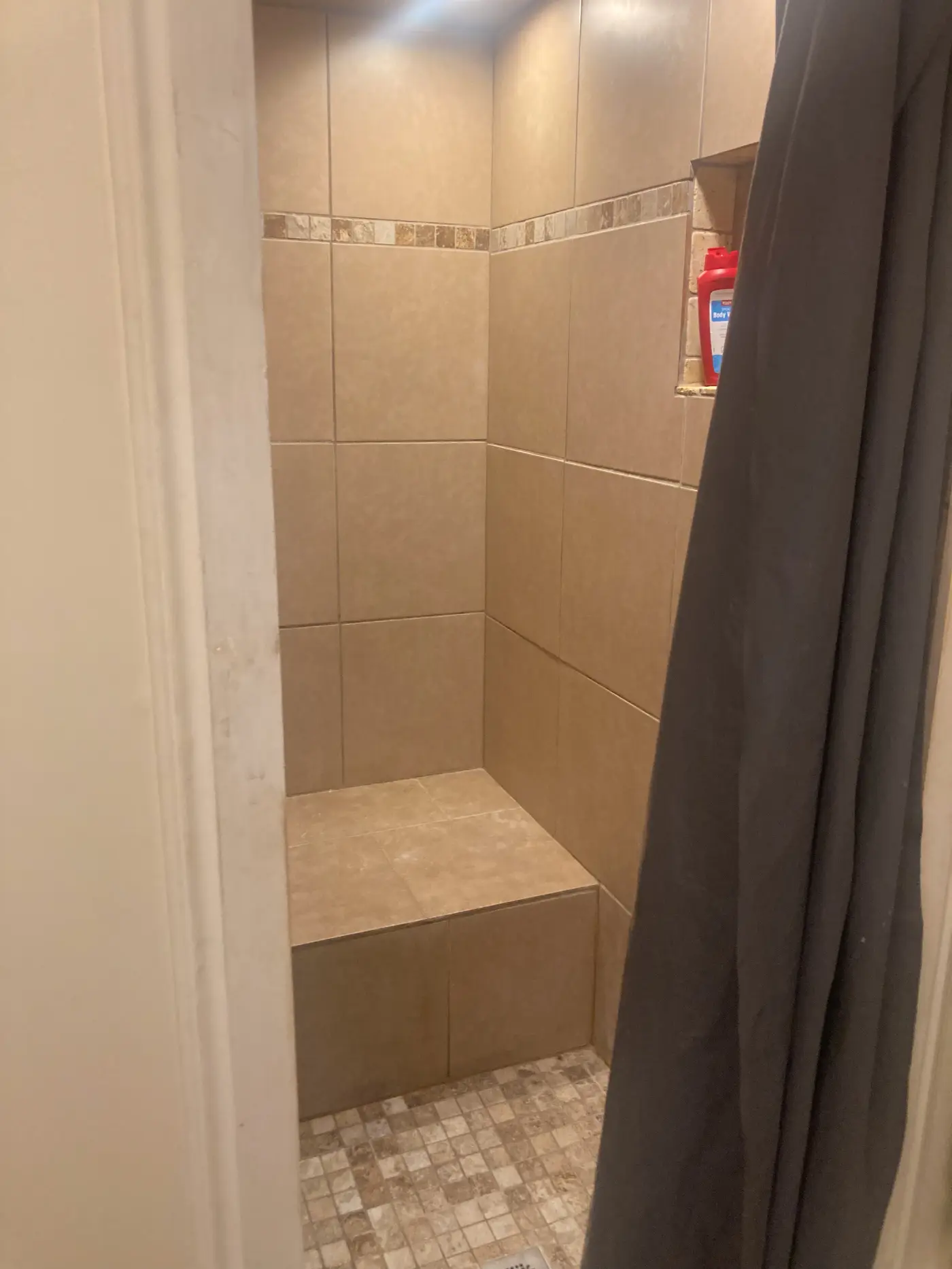 Walk-in shower with a tiled bench and a pebble floor.