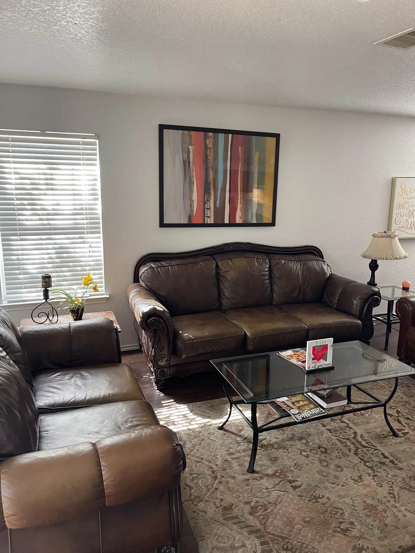Living room with brown leather sofas, table lamps and a glass coffee table.