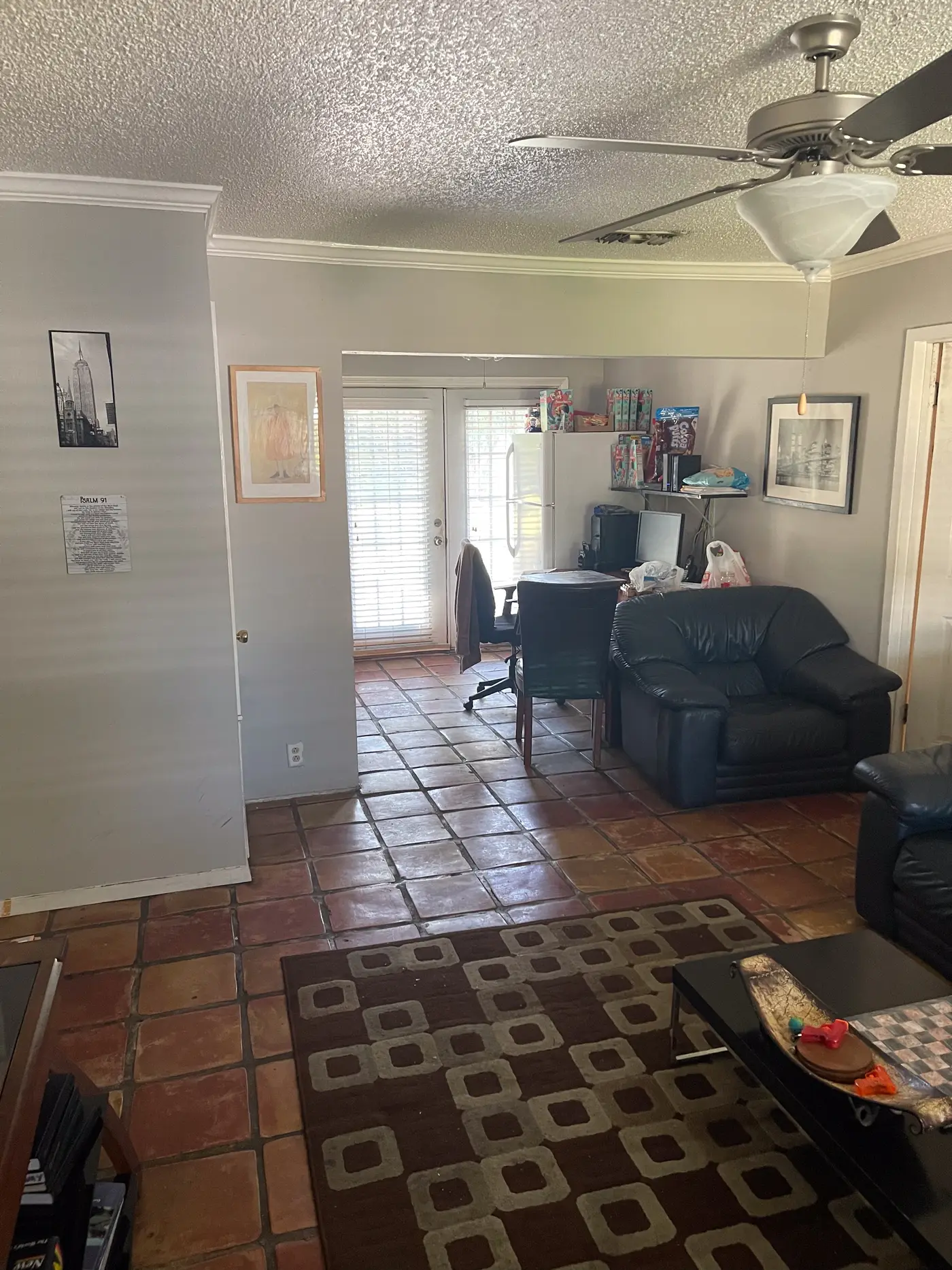 Living room with a leather sectional and a coffee table on tiled flooring.