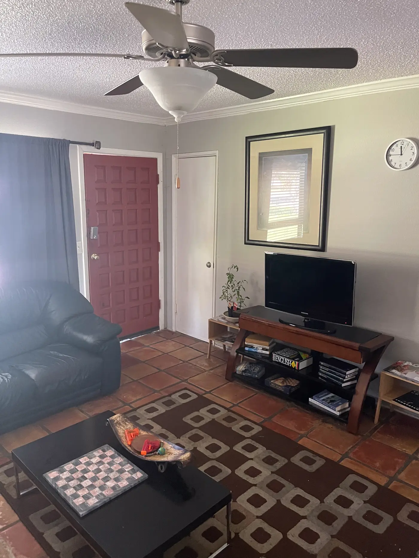 Living room with a wall-mounted television looking through to the entrance.