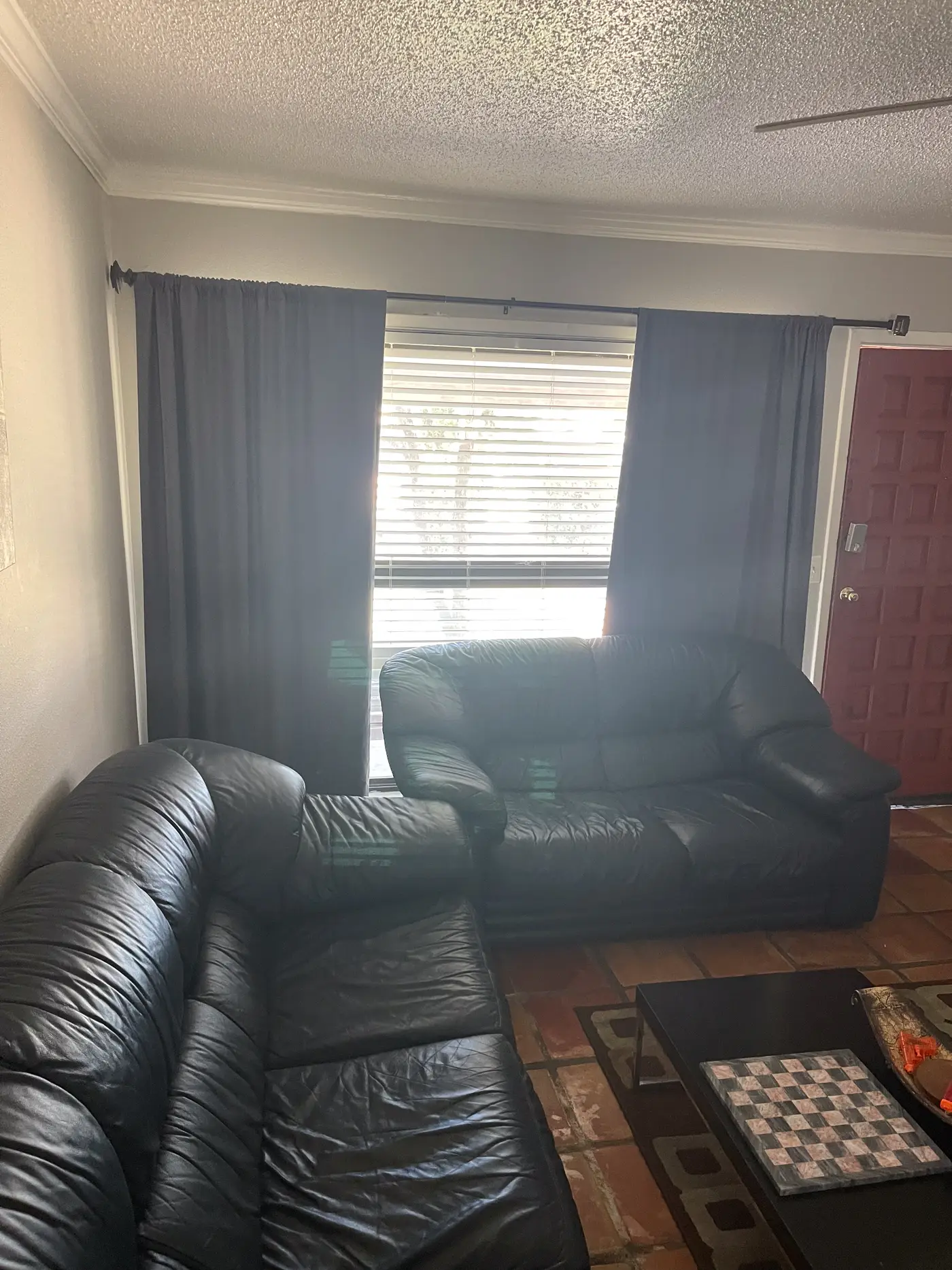 Living room with a leather sofa beside a curtained window.