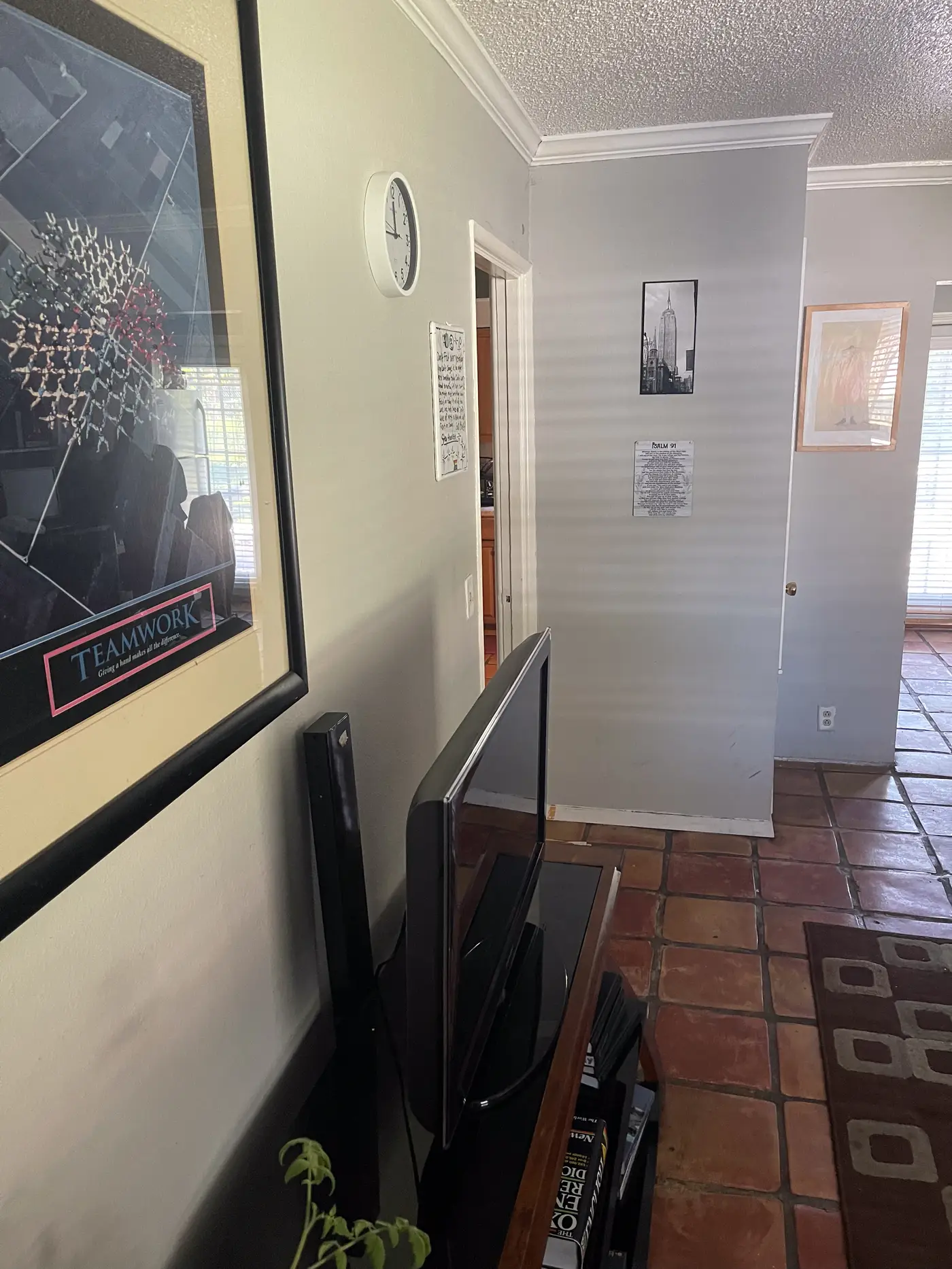 Living room corner with a television and framed wall art.