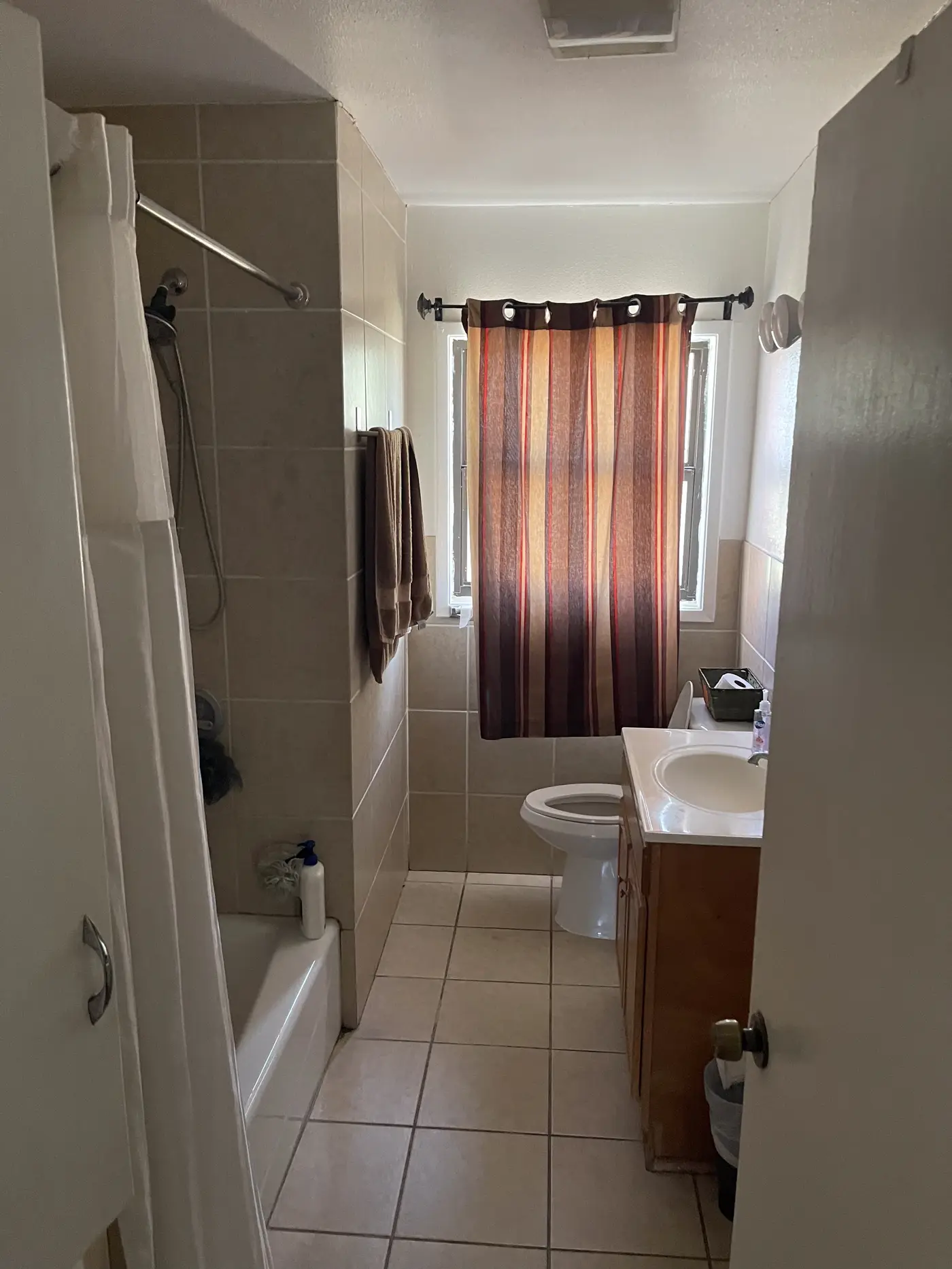 Bathroom with a bath, shower curtain and tiled floor.