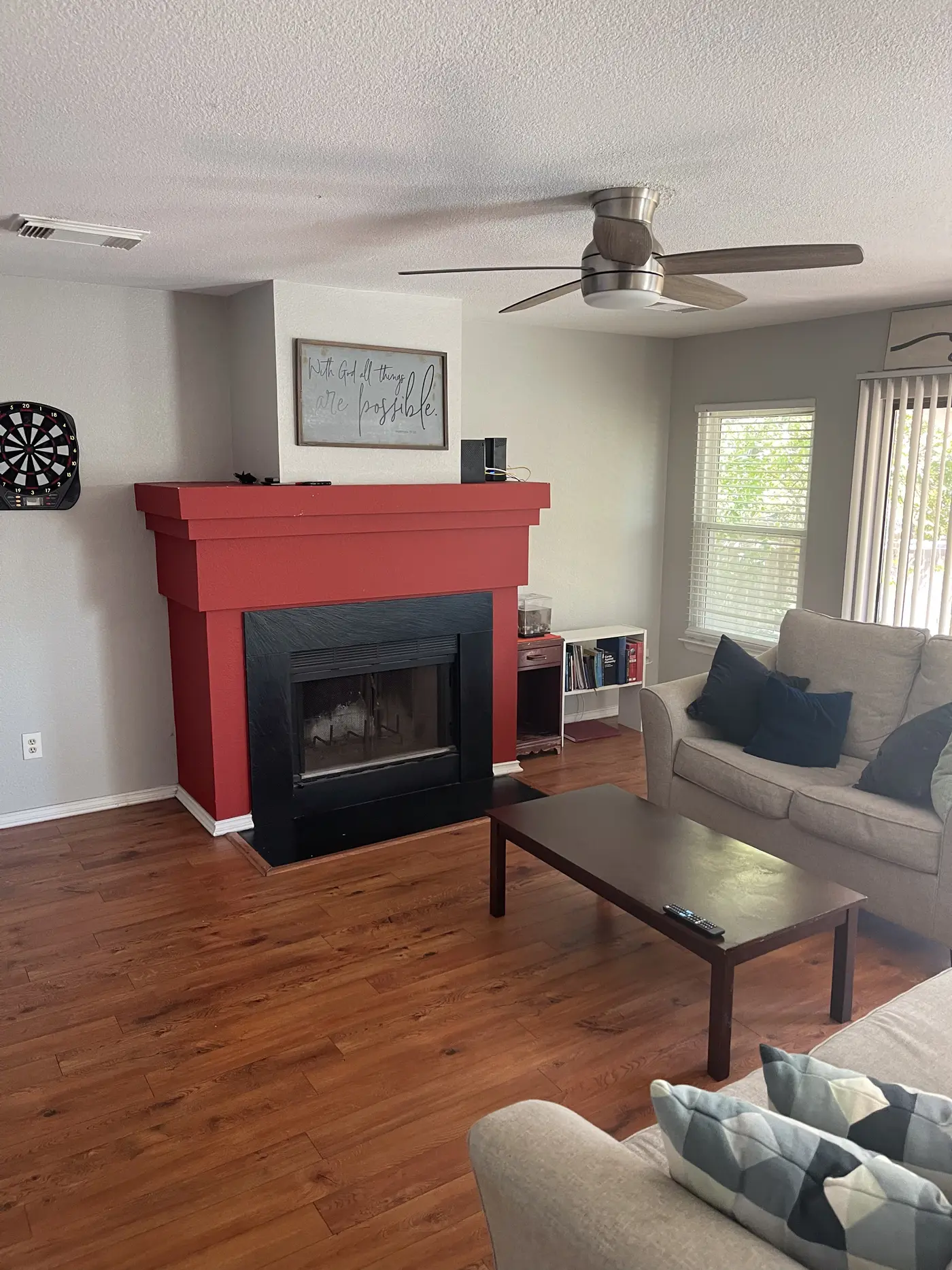 Living room with a red-painted fireplace surround, sofa and wood flooring.