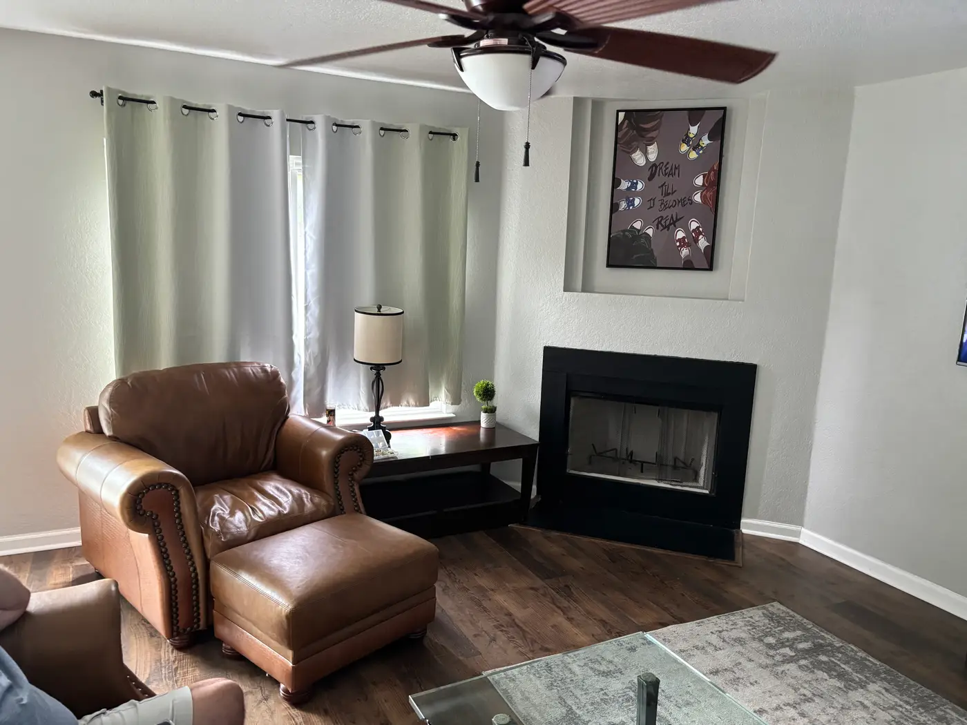 Living room with a leather armchair and footstool beside the fireplace.