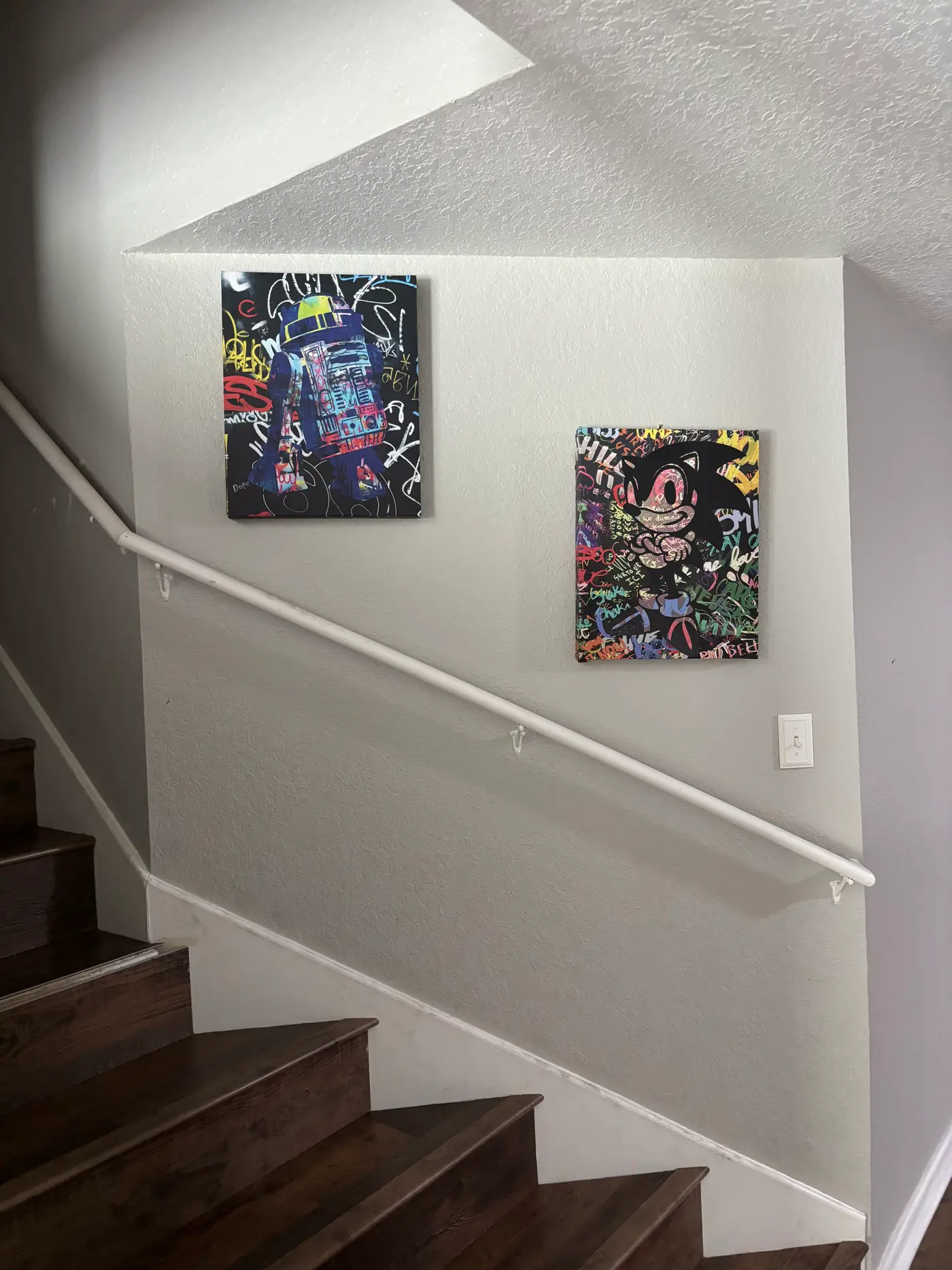 Staircase with framed prints on the wall above dark wood treads.