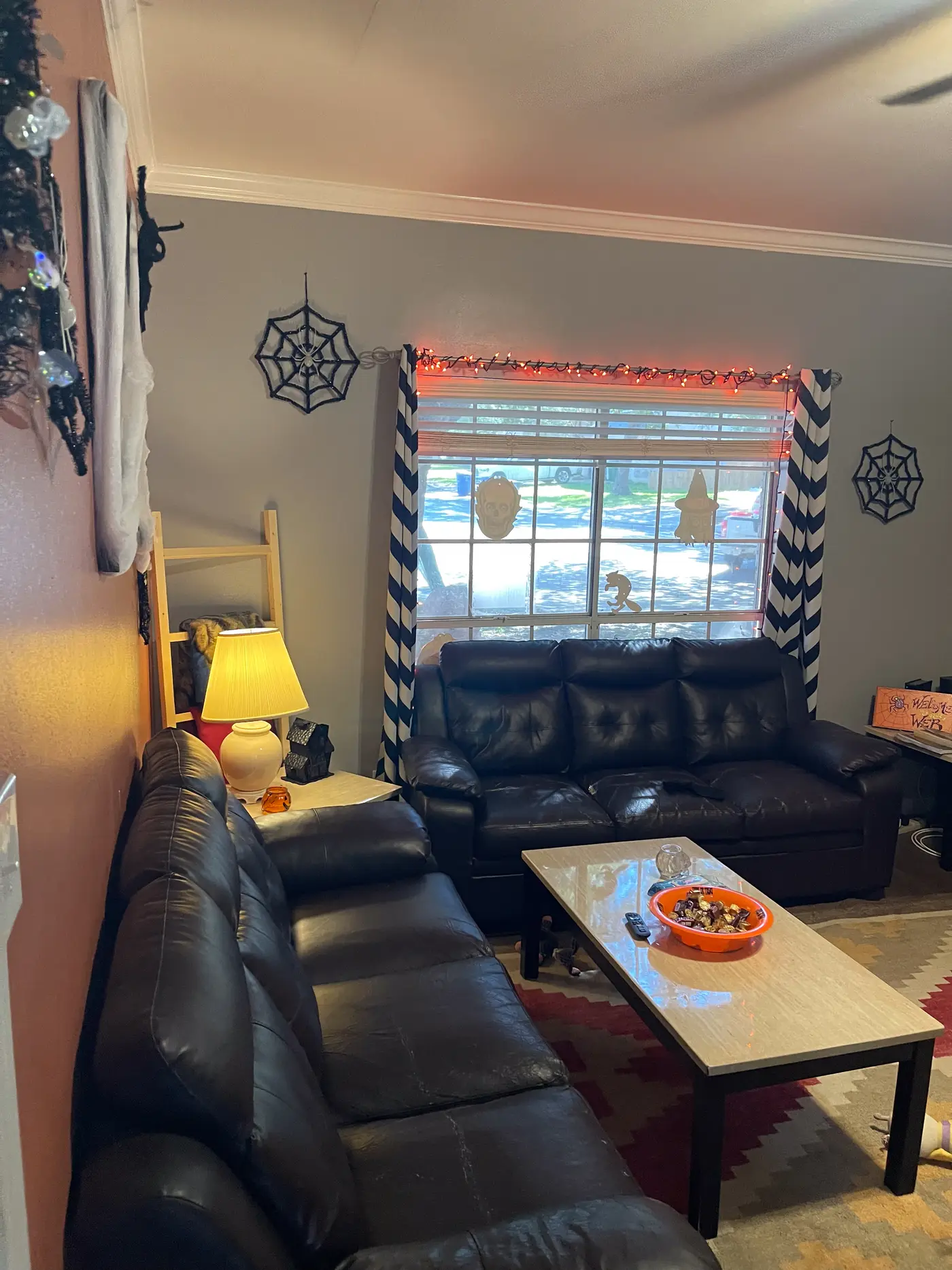 Living room with a leather sectional, coffee table and curtained window.