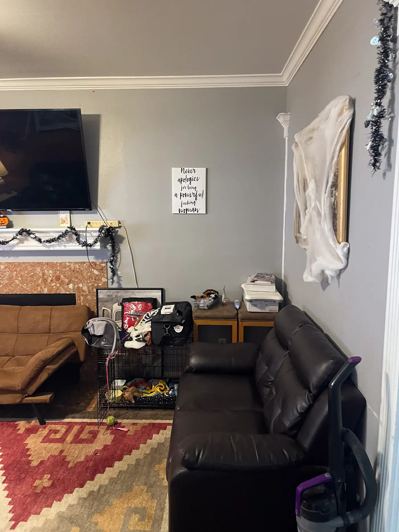 Living room corner with a television above the fireplace and framed wall art.