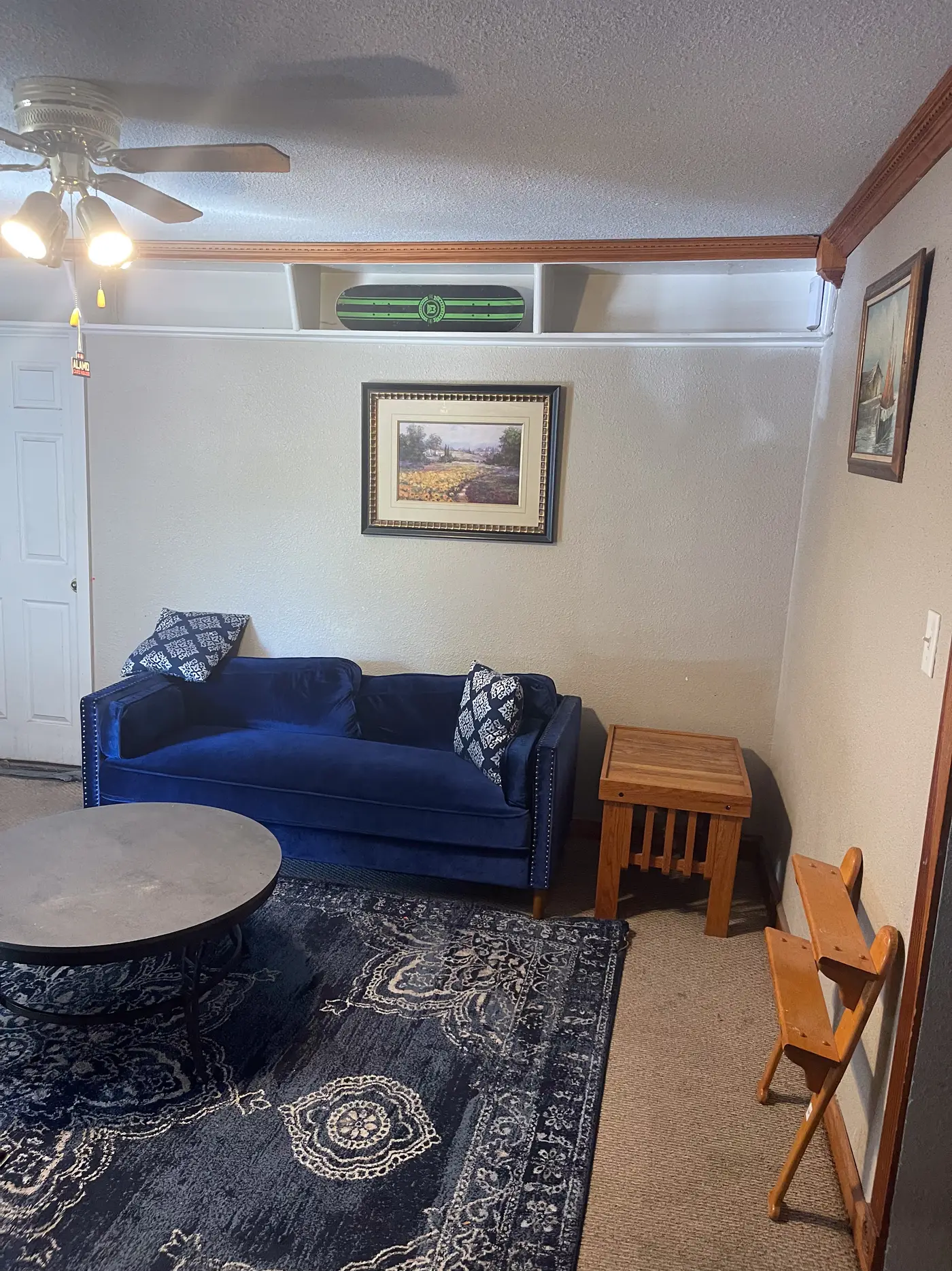Sitting room with a navy loveseat on a patterned rug.