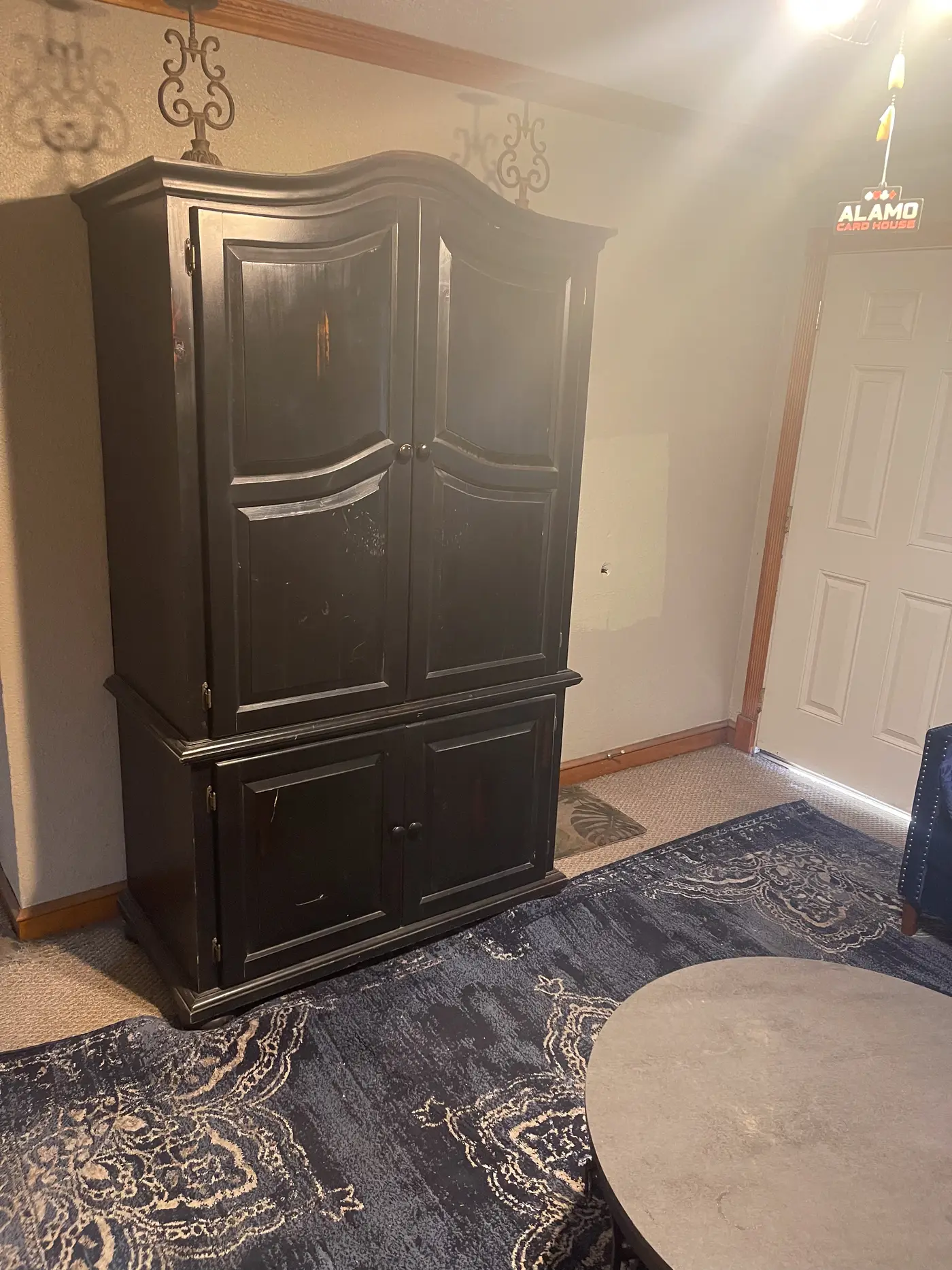 Dark wooden armoire in a room with a patterned rug.