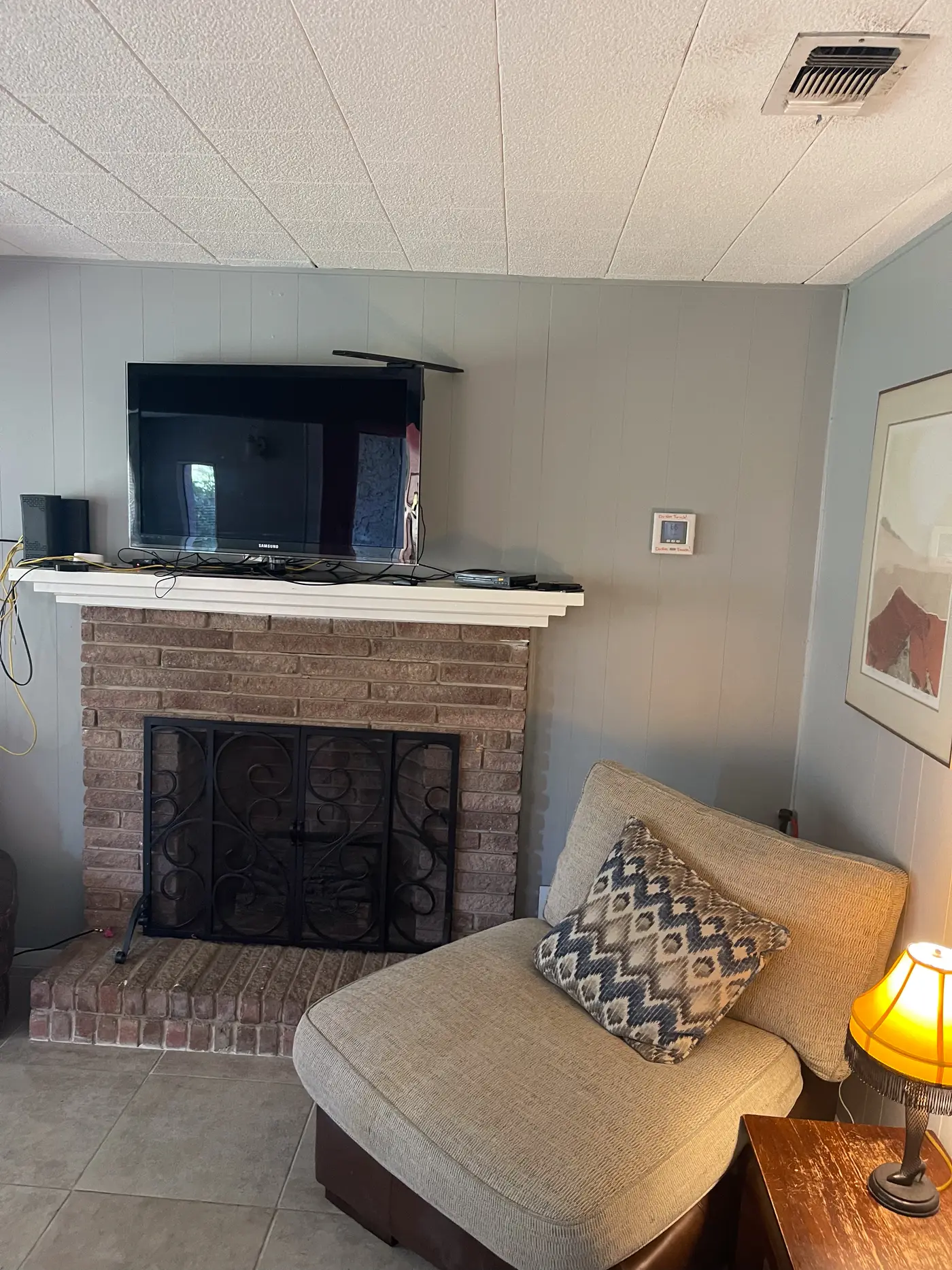 Living room with a brick fireplace, wall-mounted television and armchair.