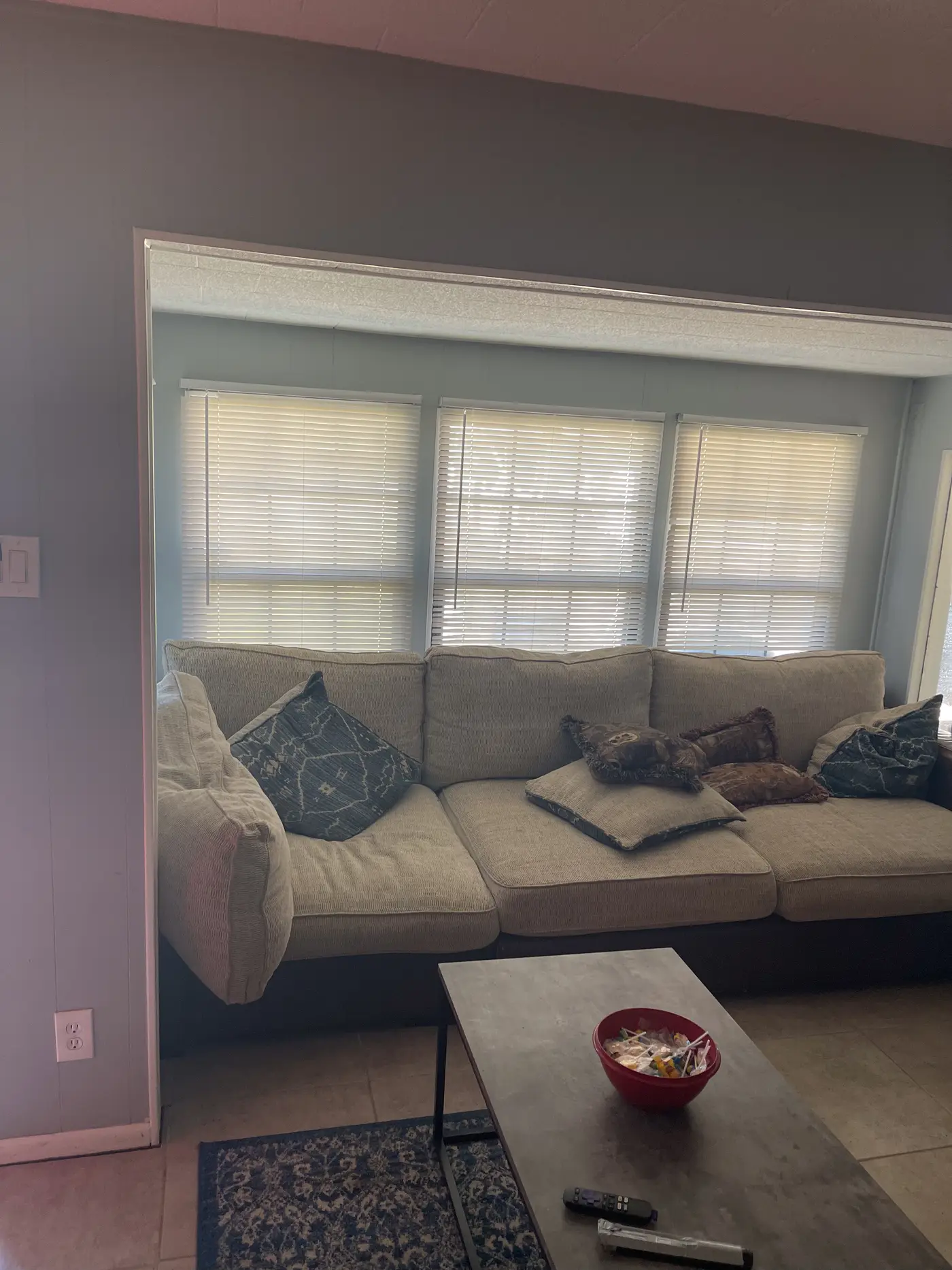 Living room with a sofa and coffee table beside a shuttered window.