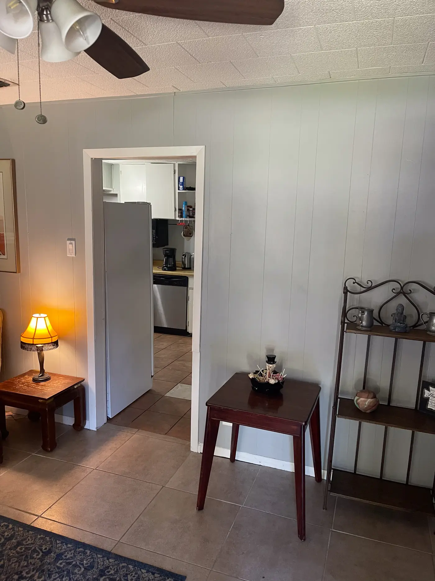 Entrance hall with a side table and lamp, looking through to the kitchen.