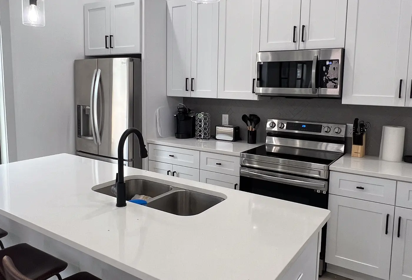 Kitchen with white cabinets, stainless range and microwave, and a quartz island.