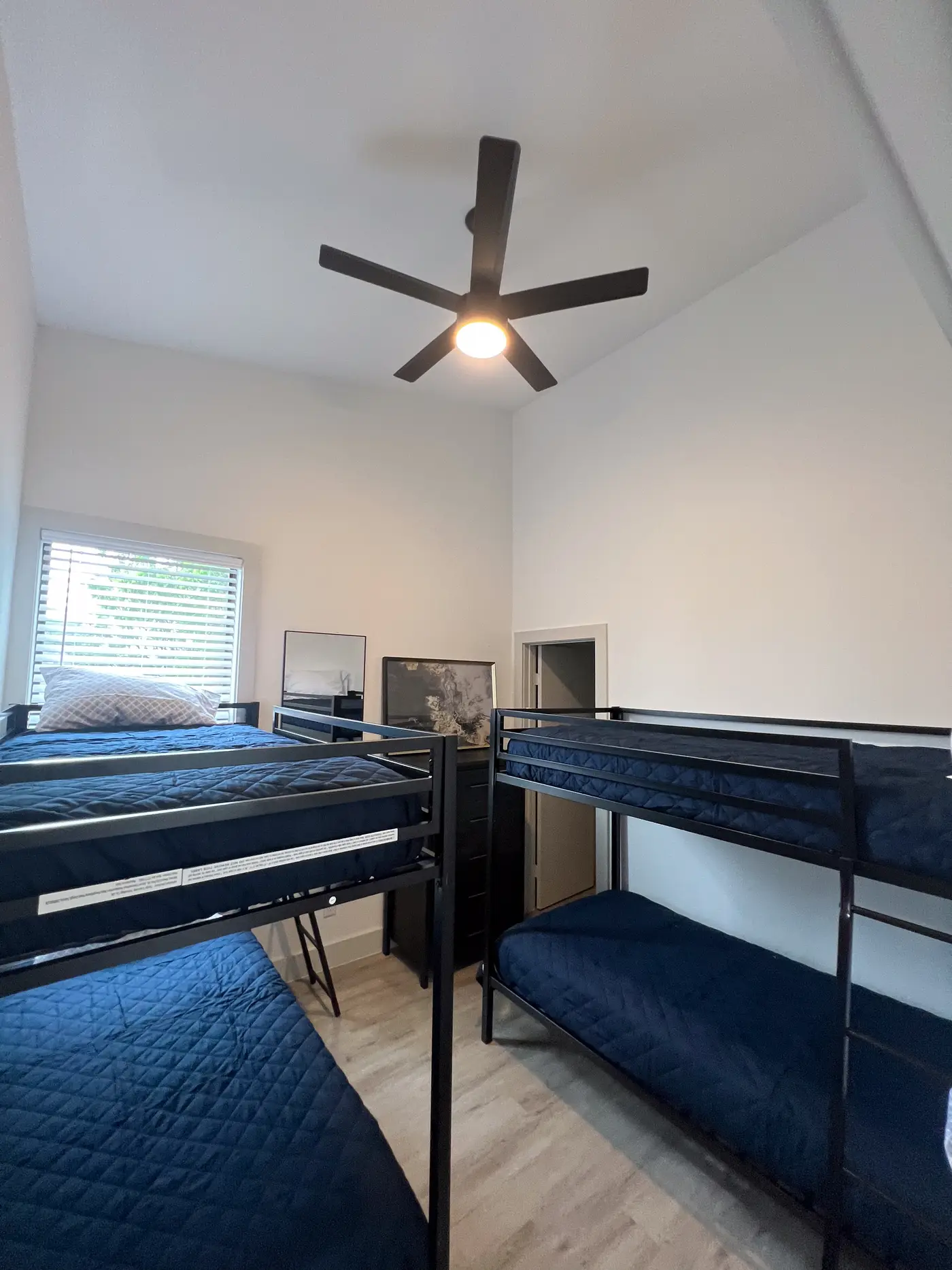 Bunk room under a vaulted ceiling with navy bedding and a ceiling fan.