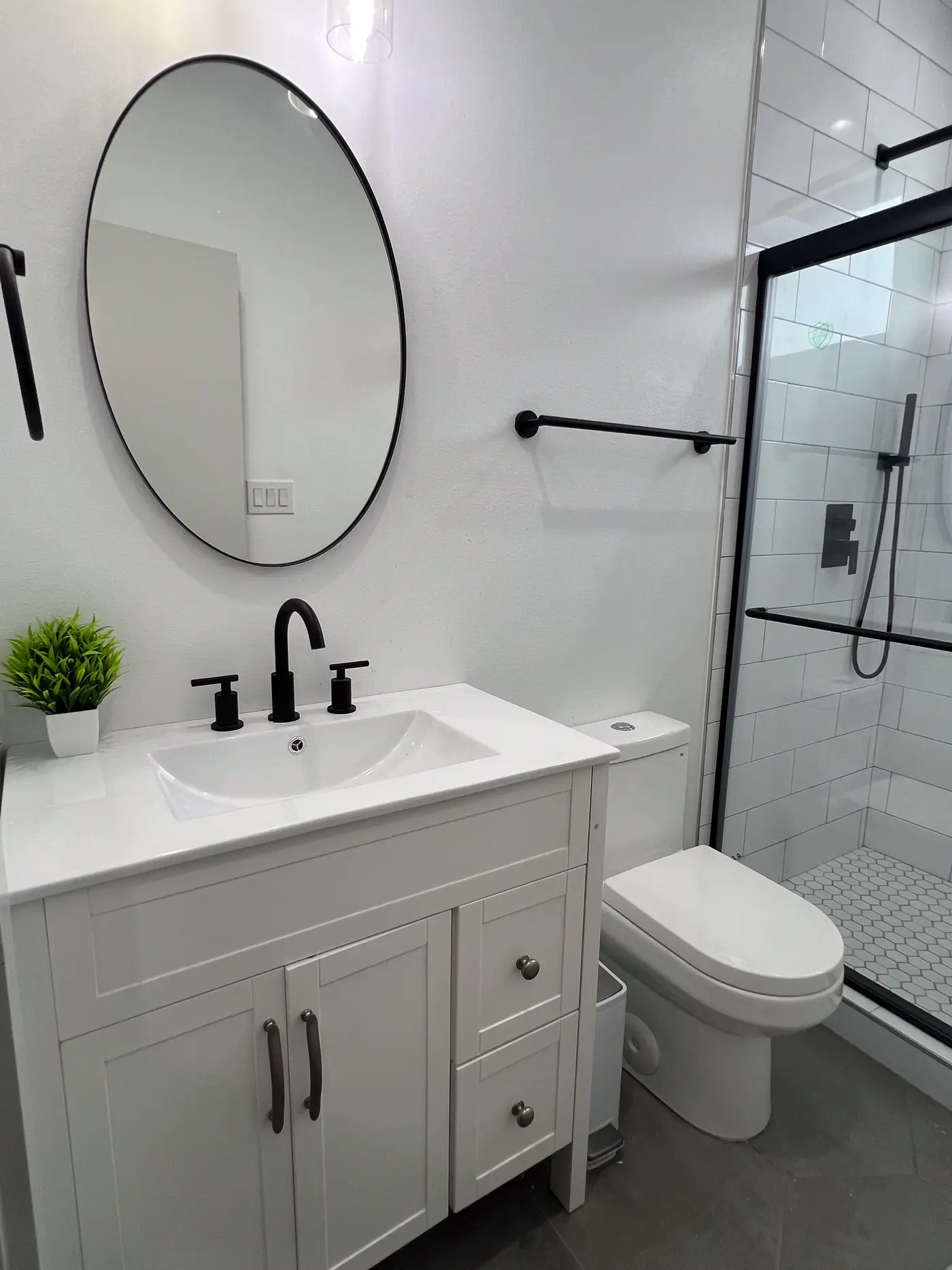 Bathroom with a white vanity, round mirror and glass-enclosed shower.