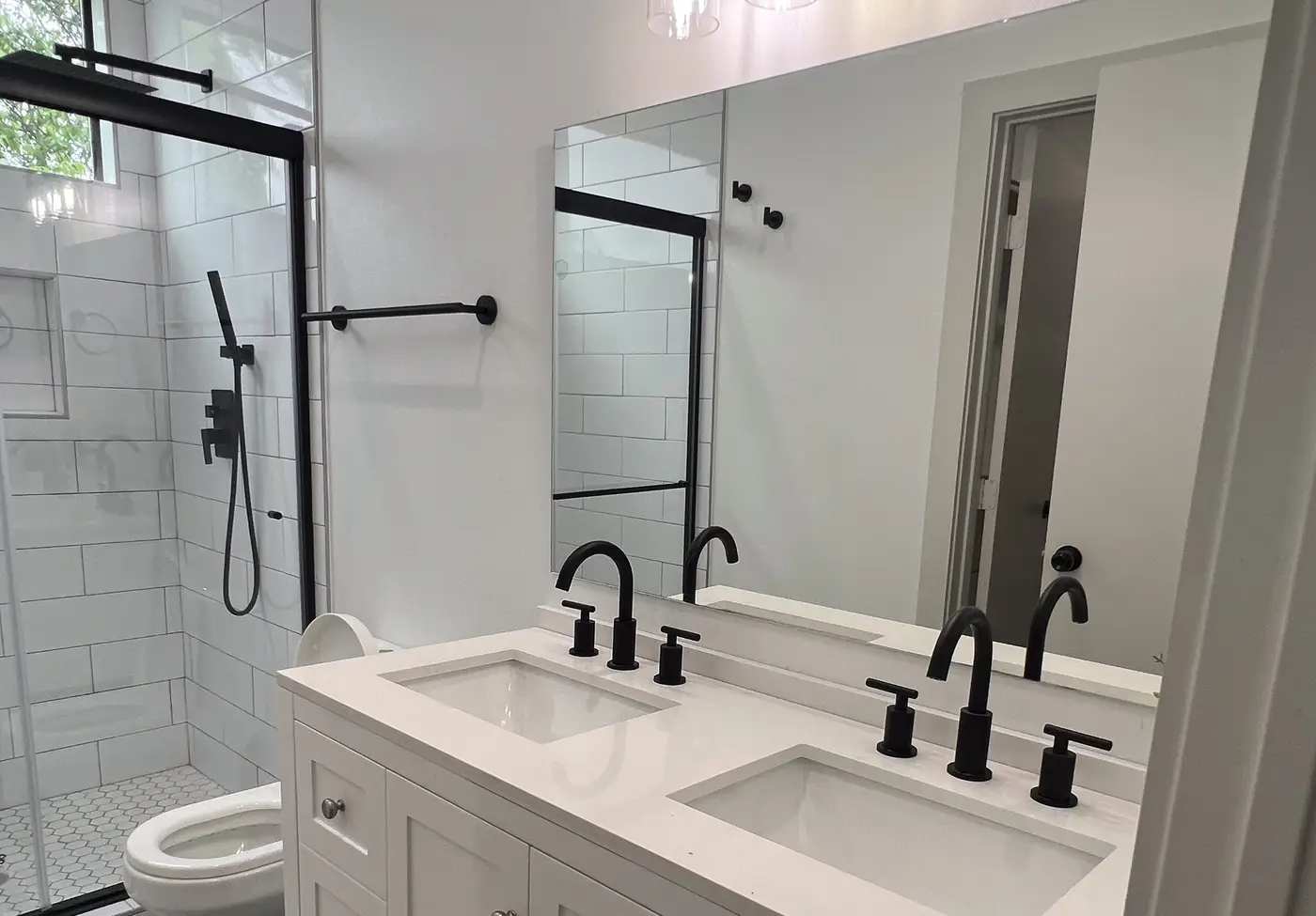 Bathroom with a double vanity, twin mirrors and black taps.