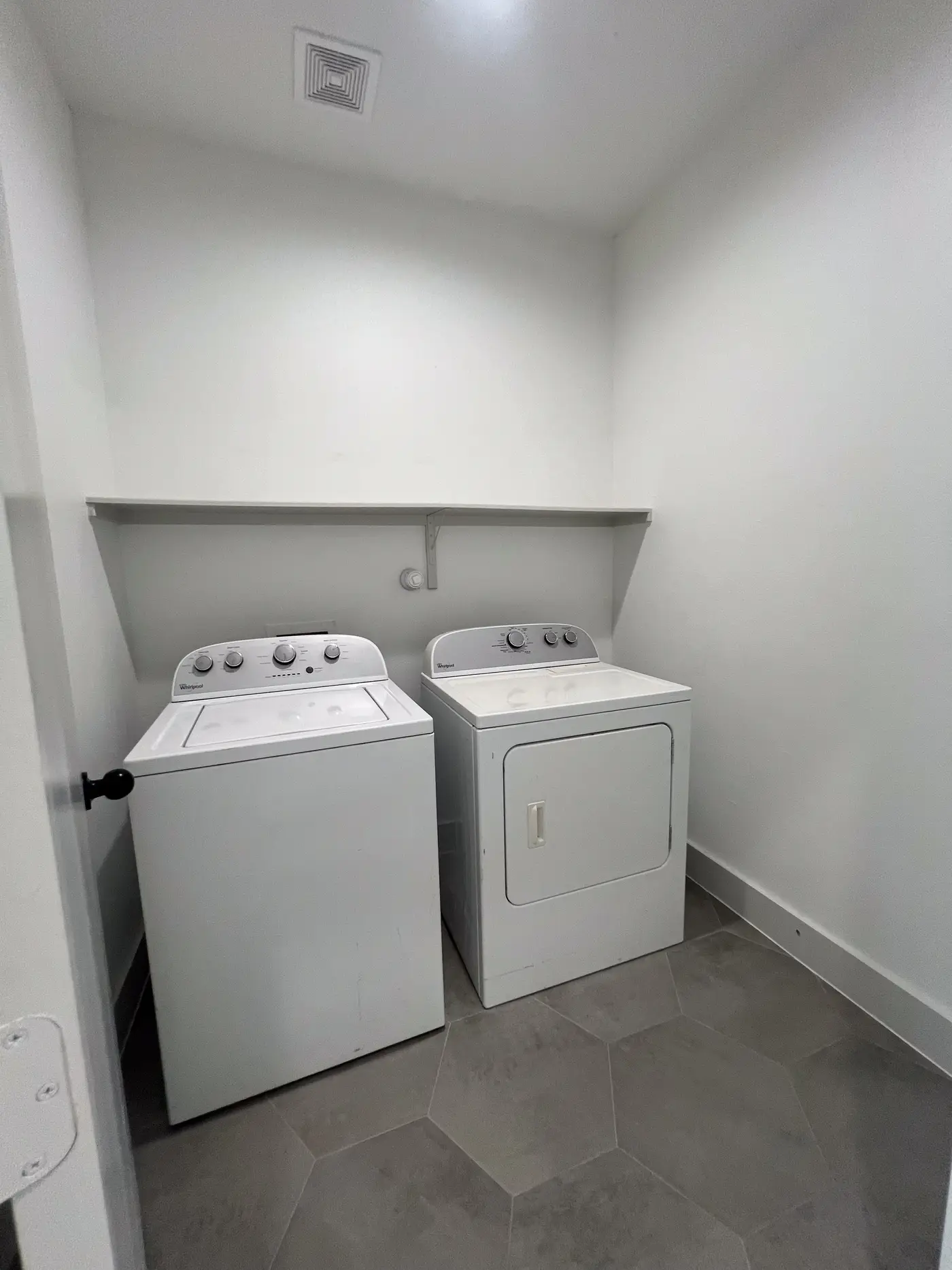 Laundry room with a washer and dryer beside a white doorway.