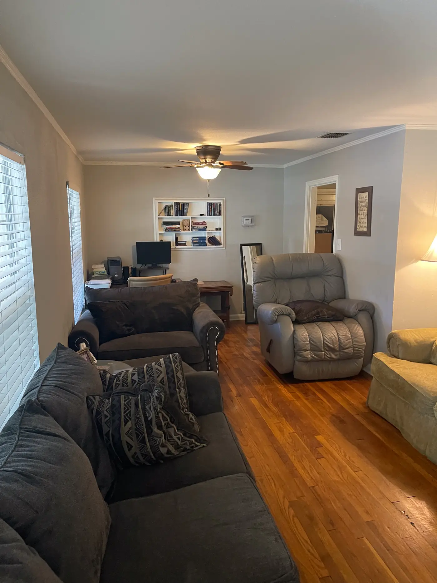 Living room with a gray sofa and a recliner on wood flooring.