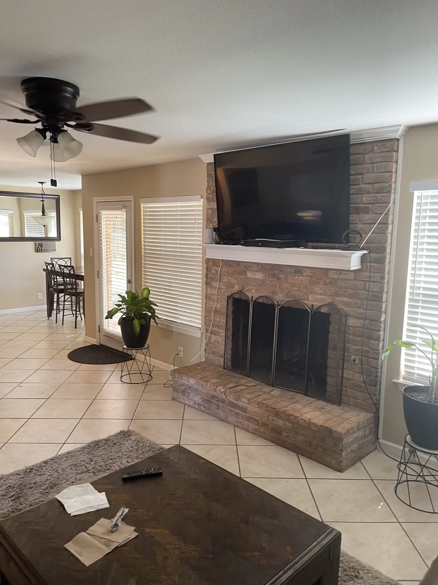 Living room with a television above the fireplace, looking toward the kitchen.