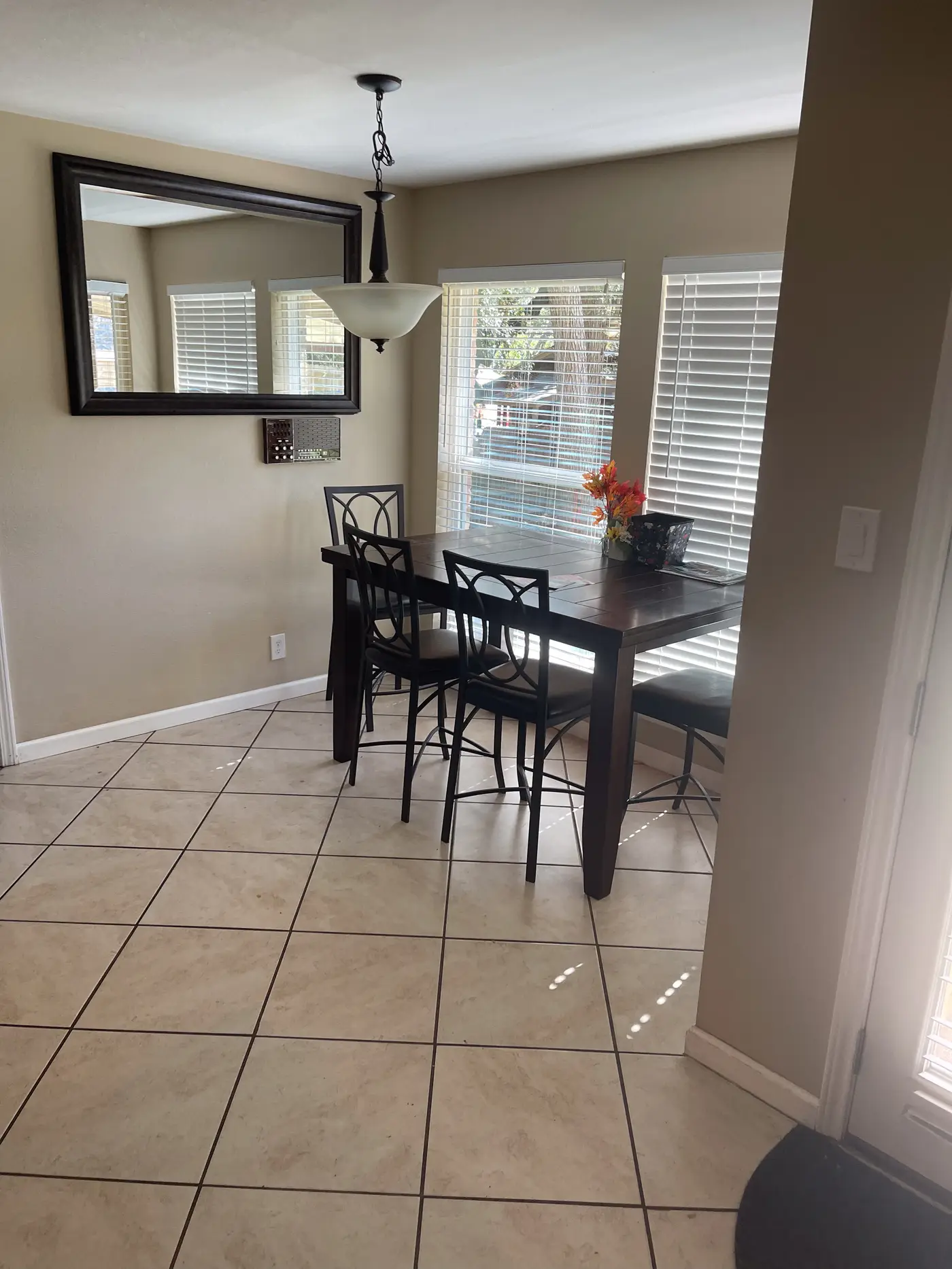 Dining room with a dark table and chairs beneath a framed mirror.