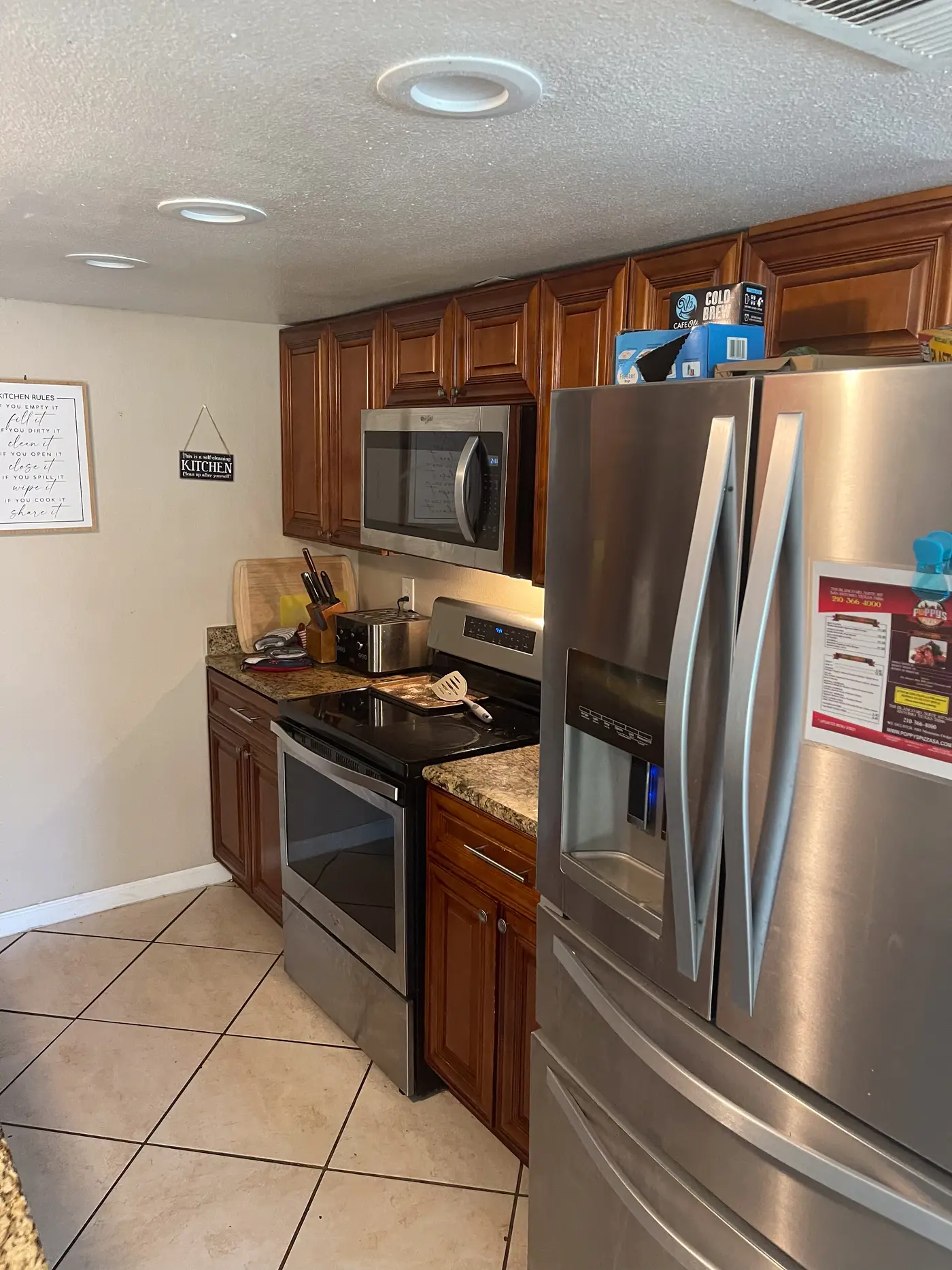 Kitchen with a stainless range and refrigerator on tiled flooring.