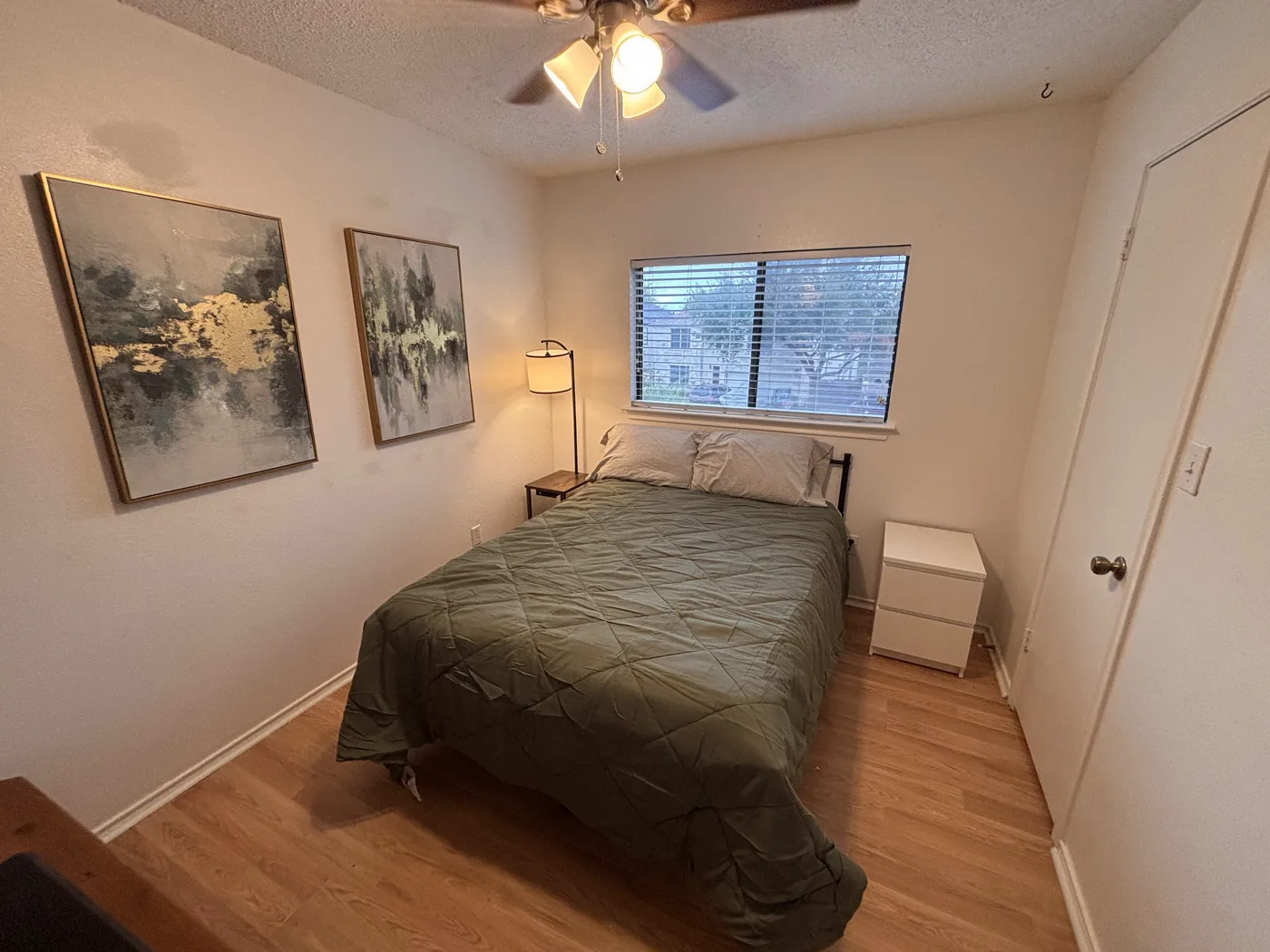 Single room with a full-size bed, two framed prints and a bedside chest.