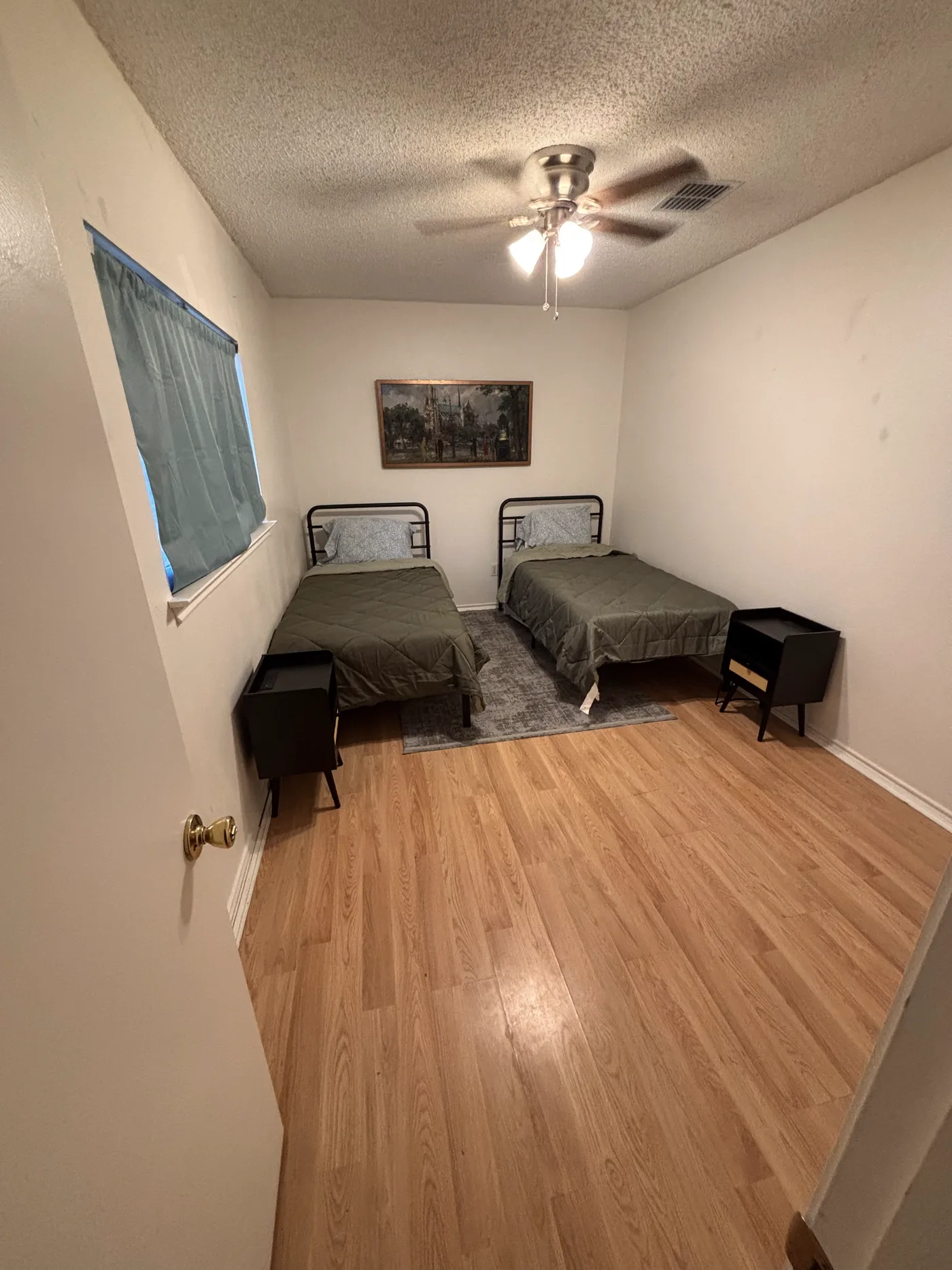 Two-bed room seen from the doorway, with a teal curtain at the window.
