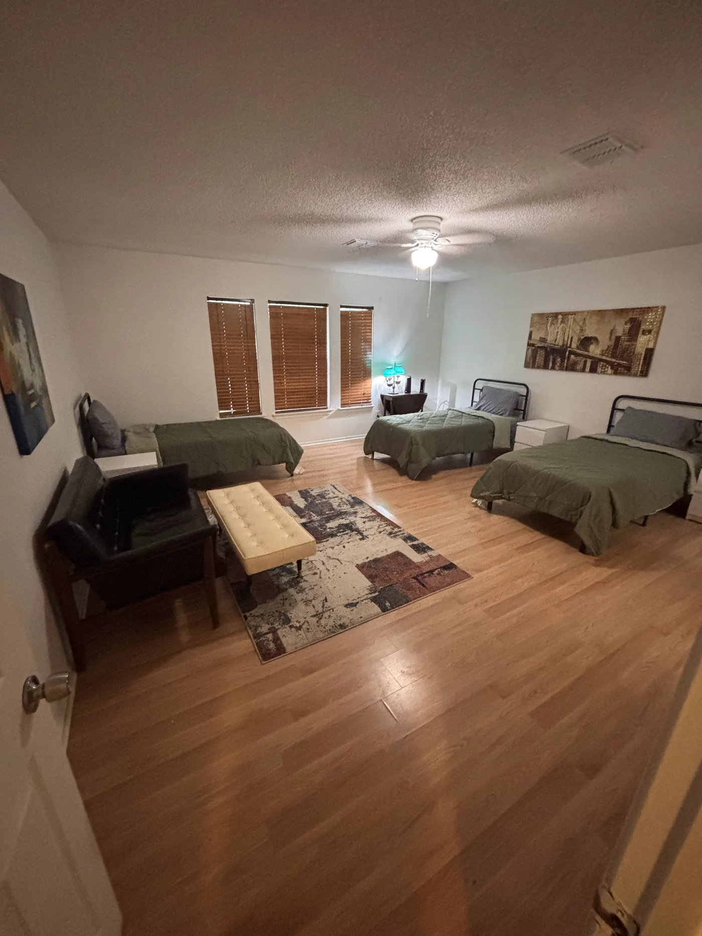 Large bedroom with three beds, a sofa and a bench set around a rug.
