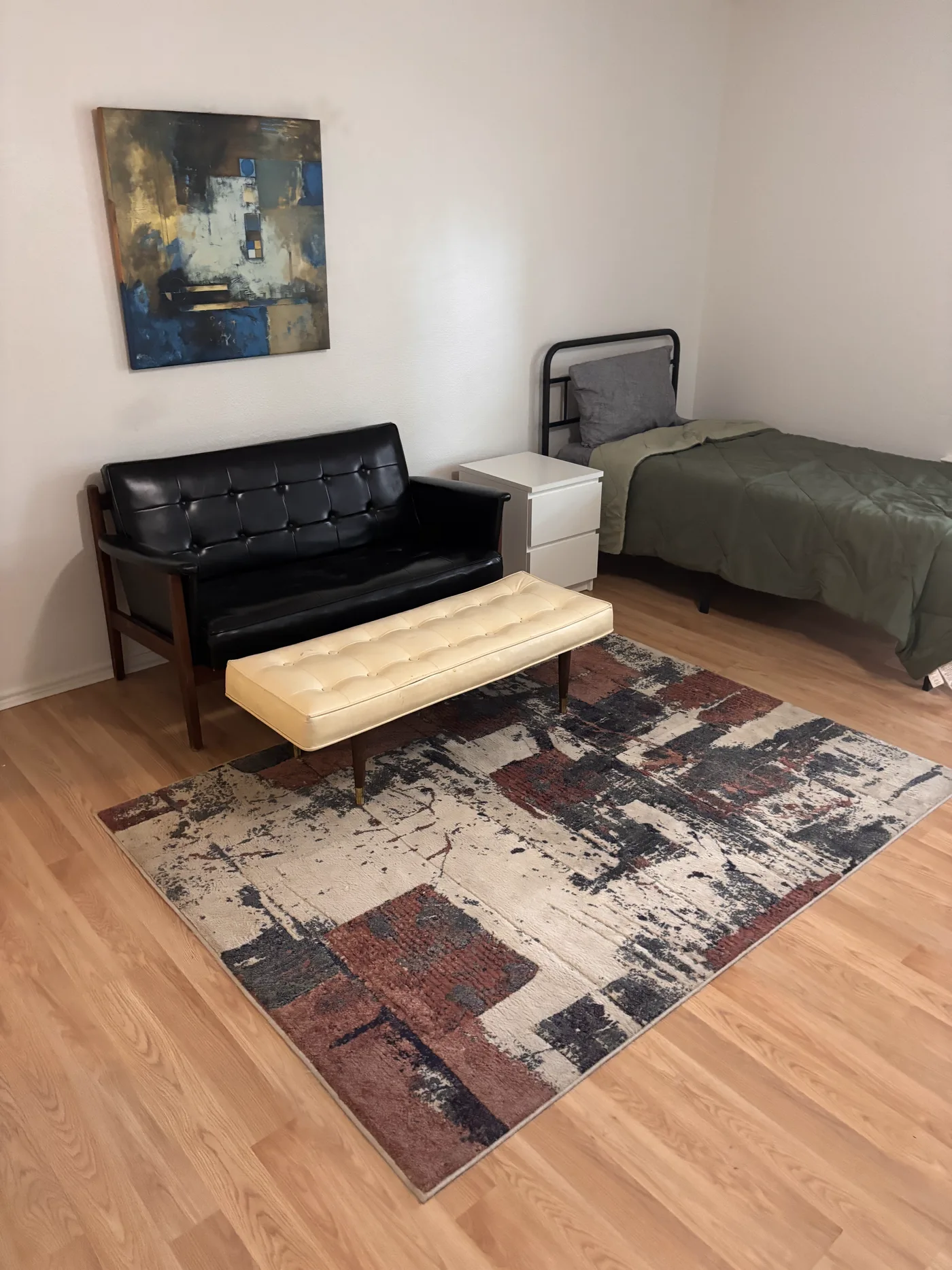 Sitting area in the three-bed room, with a leather sofa and a bench on a rug.