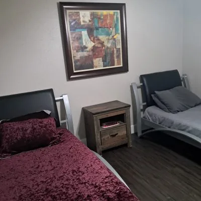 Shared two-man suite bedroom in Austin with twin beds, modern frame, and contemporary artwork