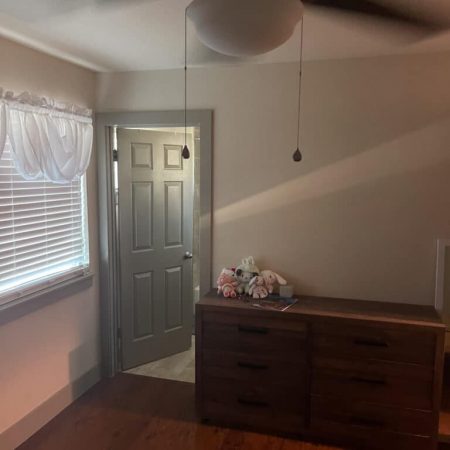 Private bedroom in Austin sober living home with dresser, ceiling fan, and natural window light
