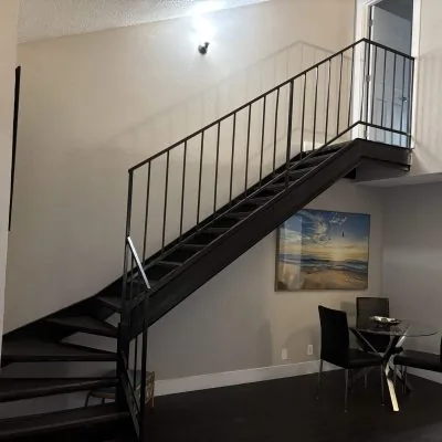 Two-bedroom men’s sober living apartment in Austin with modern staircase and dining area