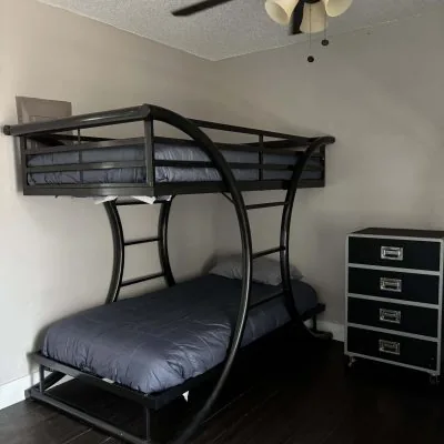 Affordable men’s sober living bedroom with black metal bunks and ceiling fan in Austin TX
