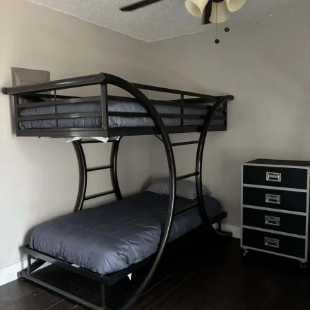 Affordable men’s sober living bedroom with black metal bunks and ceiling fan in Austin TX